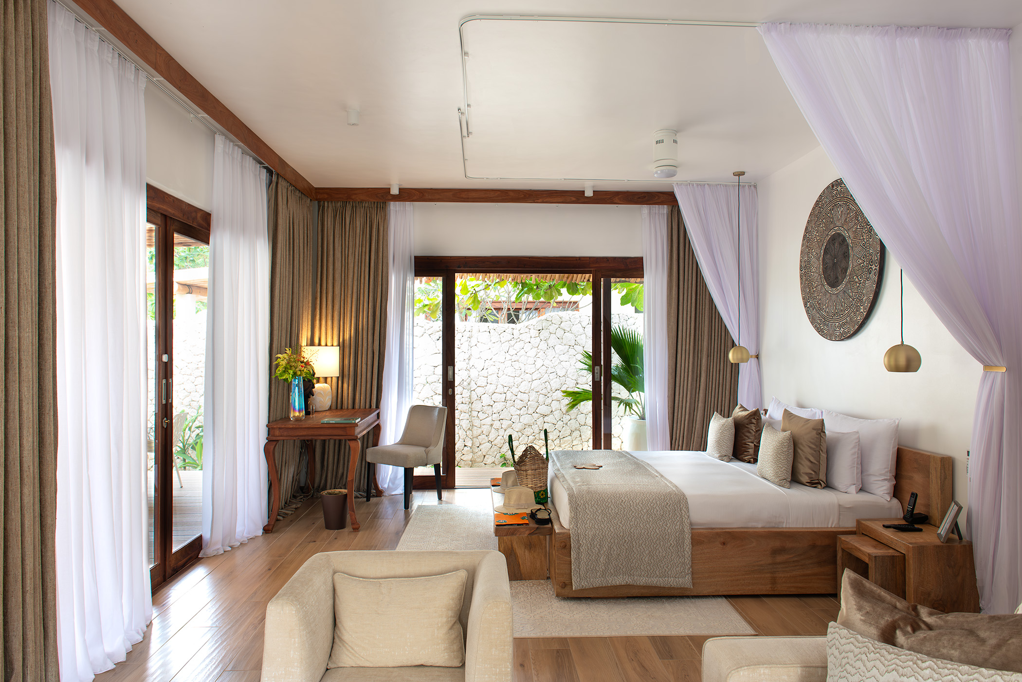 Elegant bedroom with a wooden bed, sheer curtains, and a garden view.