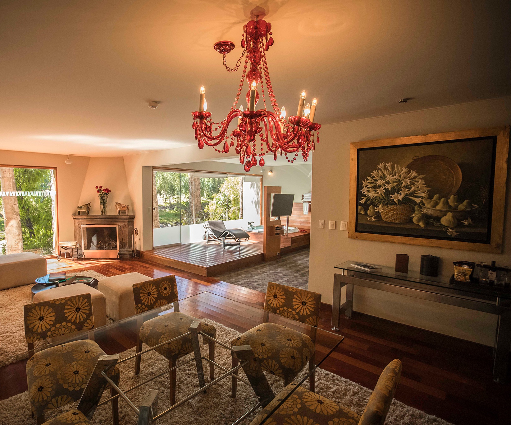 Elegant living room interior with red chandelier, hardwood floors, and large window with garden view.
