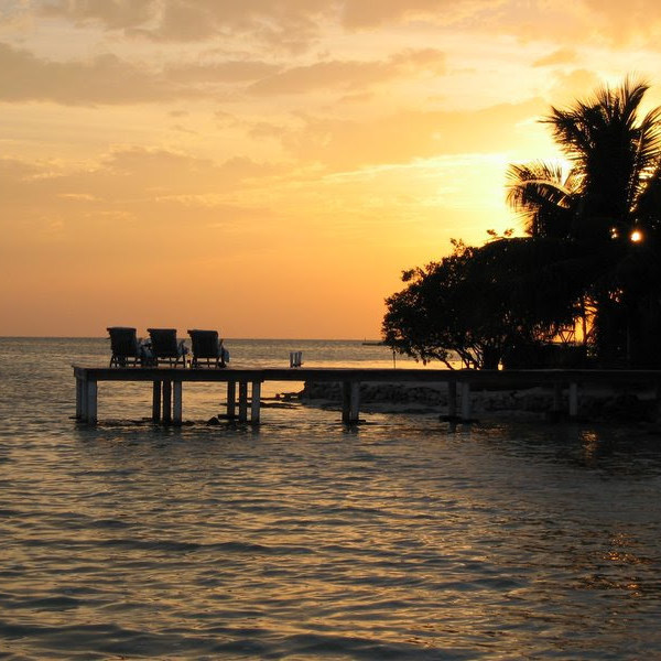 The private dock of one of Cayo Espanto's private villas at sunset, featuring a pair of sun loungers.