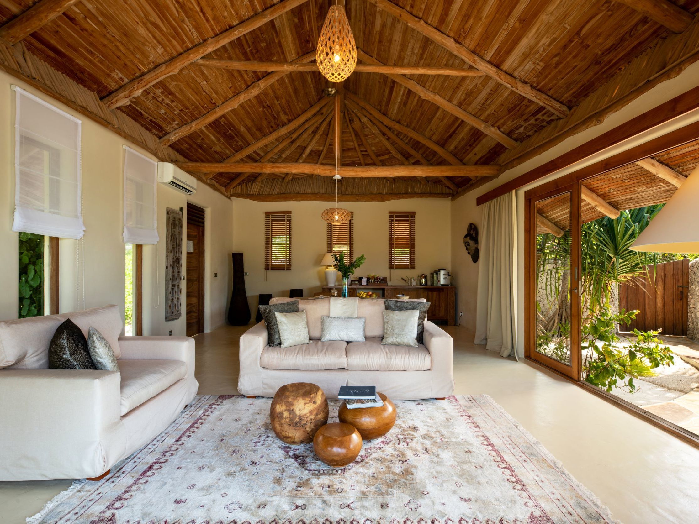 Spacious living room with a vaulted bamboo ceiling, plush sofas, and tropical outdoor views.