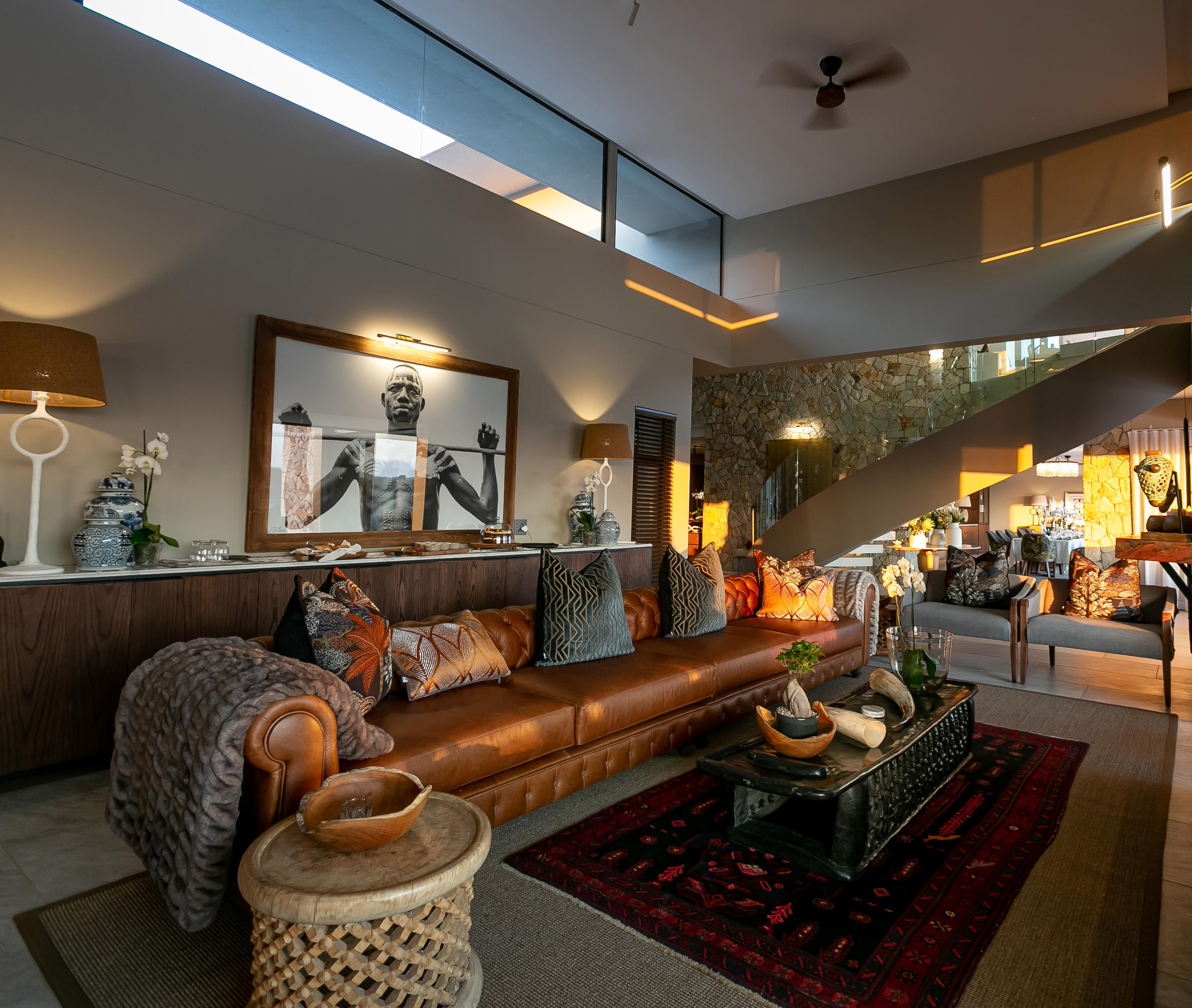 Elegant living room with leather sofa, decorative pillows, a wooden coffee table, and ambient lighting.