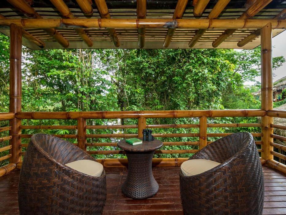 A panoramic terrace at La Selva Lodge where two chairs and a table overlook the forest ahead.