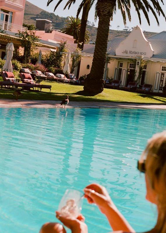 Outdoor swimming pool looking towards a white building labeled Librisa Spa with pink hotel buildings in the background.