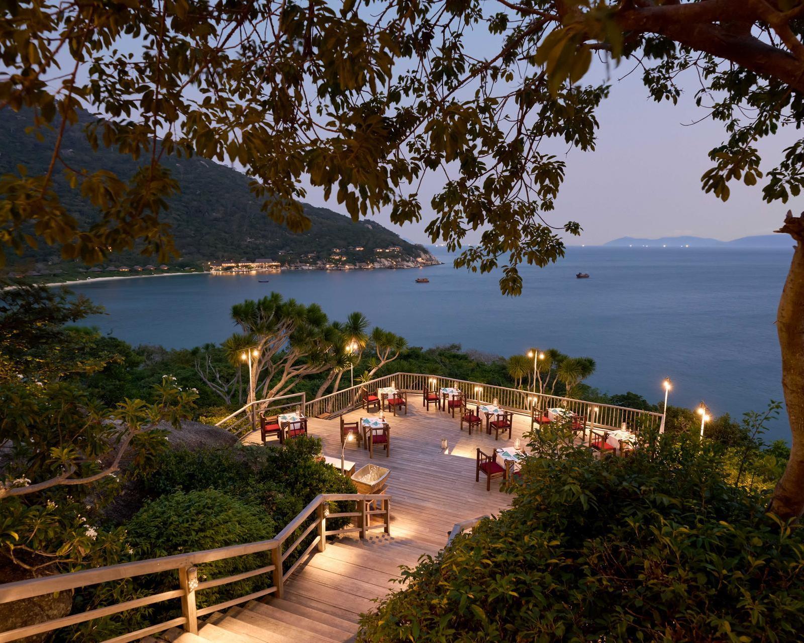Outdoor dining set up with lights at dusk at Six Senses Ninh Van Bay