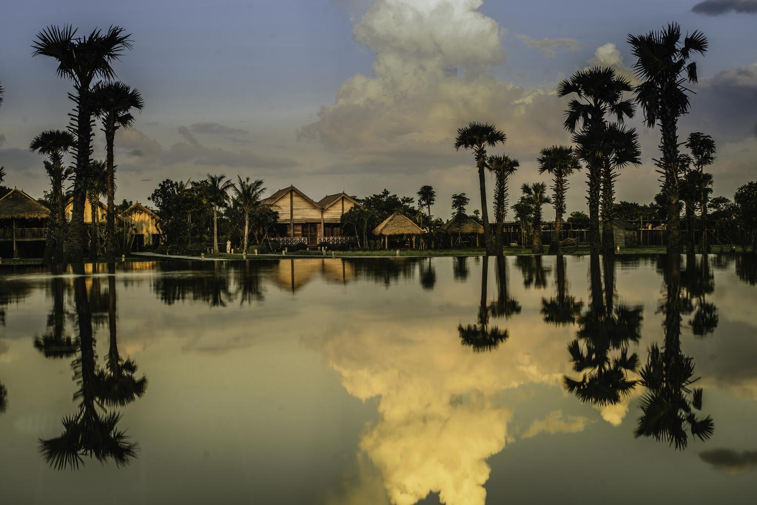 Reflection of hotel and palm trees in the pool at Zannier Phum Baitang