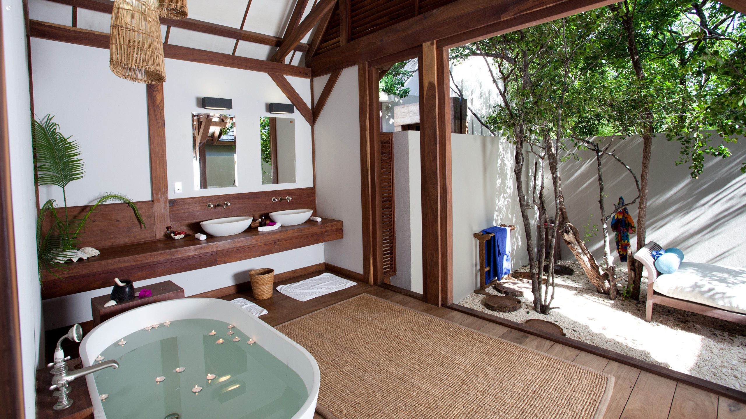 Lush tropical villa with a private pool, framed by trees and featuring a thatched-roof design and cozy outdoor seating.