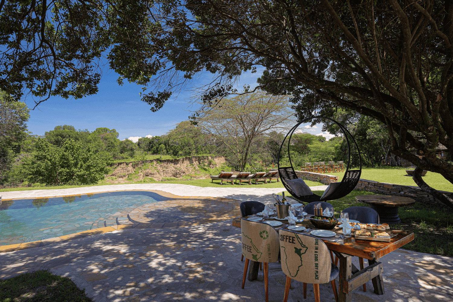 Outdoor dining set up next to a pool at House in the Wild