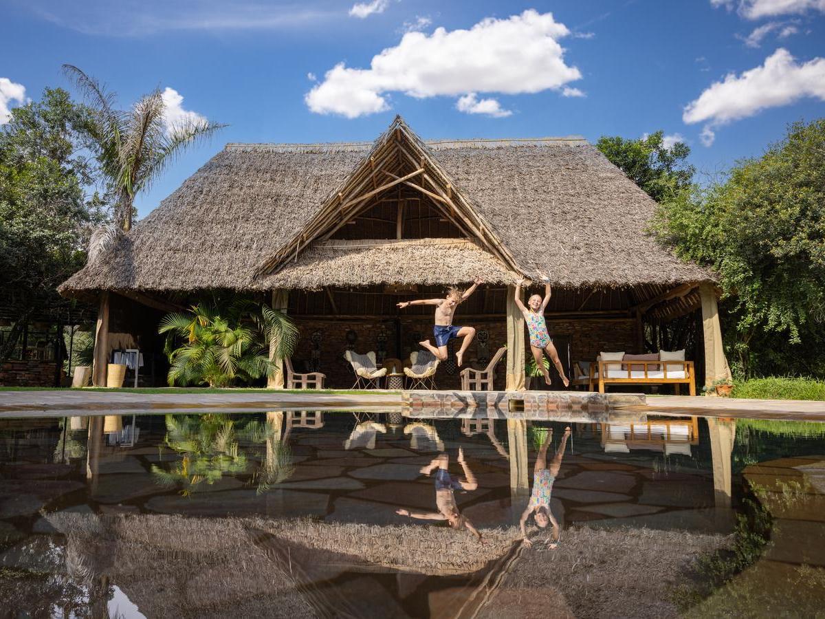 Two children jumping into an outdoor pool at House in the Wild