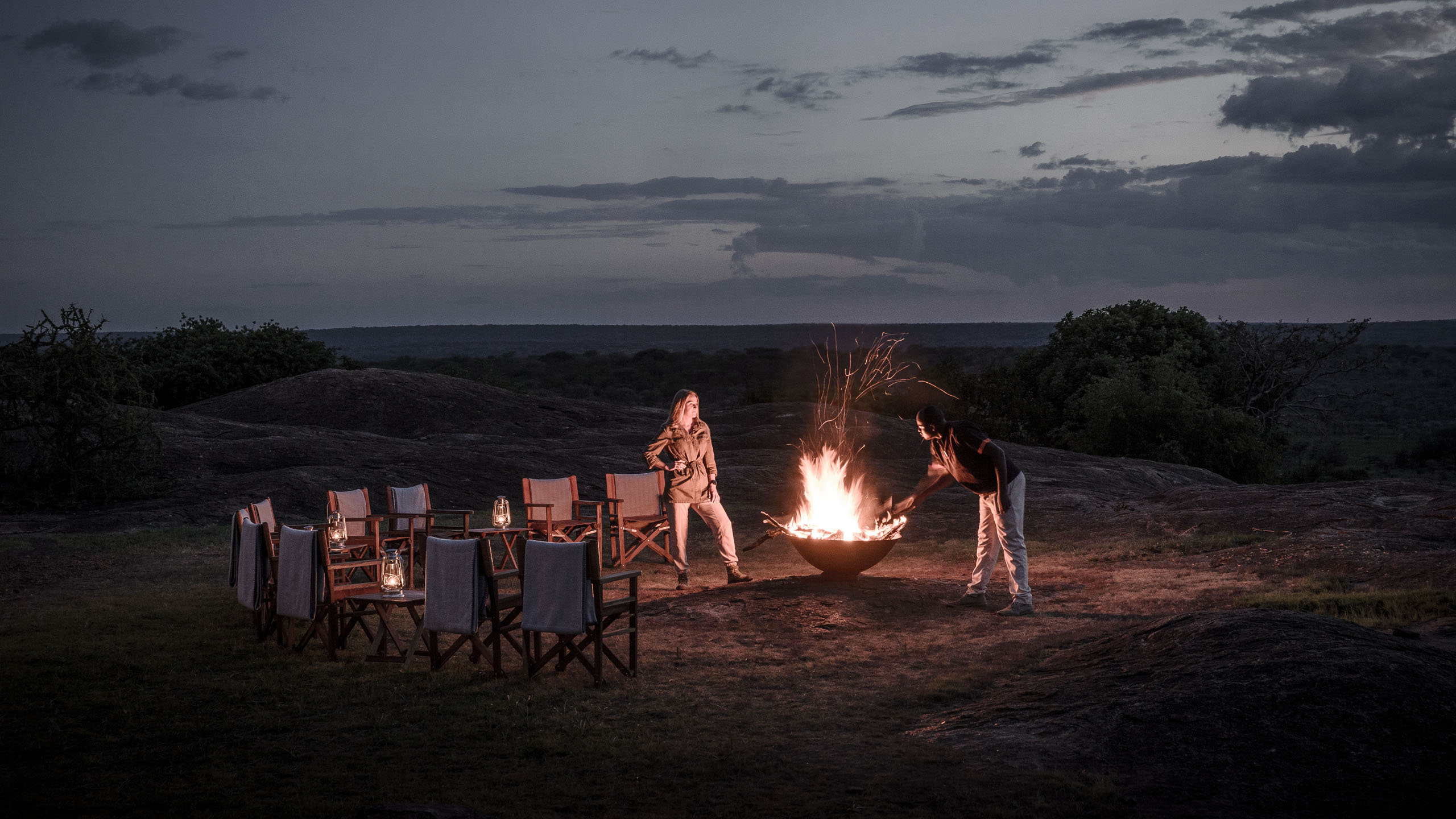 Two people around a fire at night in the Serengeti