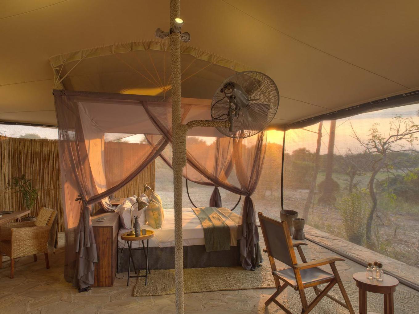 A view of one of Roho ya Selous's bedrooms from inside, featuring a canopy bed overlooking the bush.