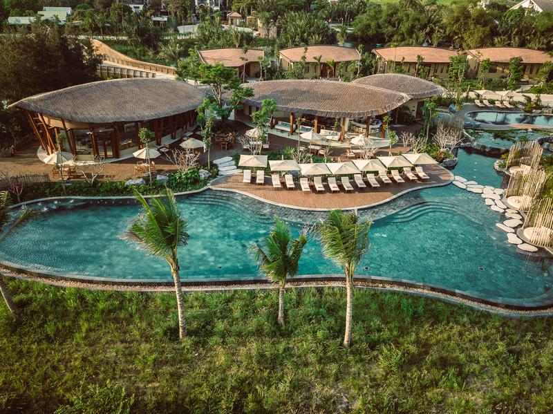 Aerial view of Namia River Retreat's lagoon swimming pool, sun loungers and tropical architecture.