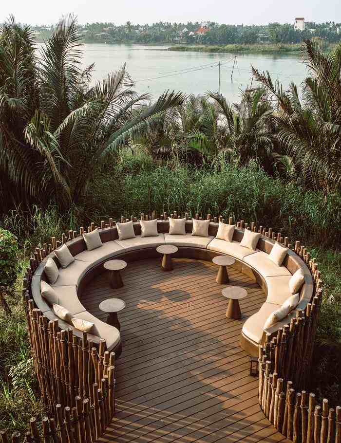 A circular wooden outdoor seating area with cushions overlooking the river at Namia River Retreat.