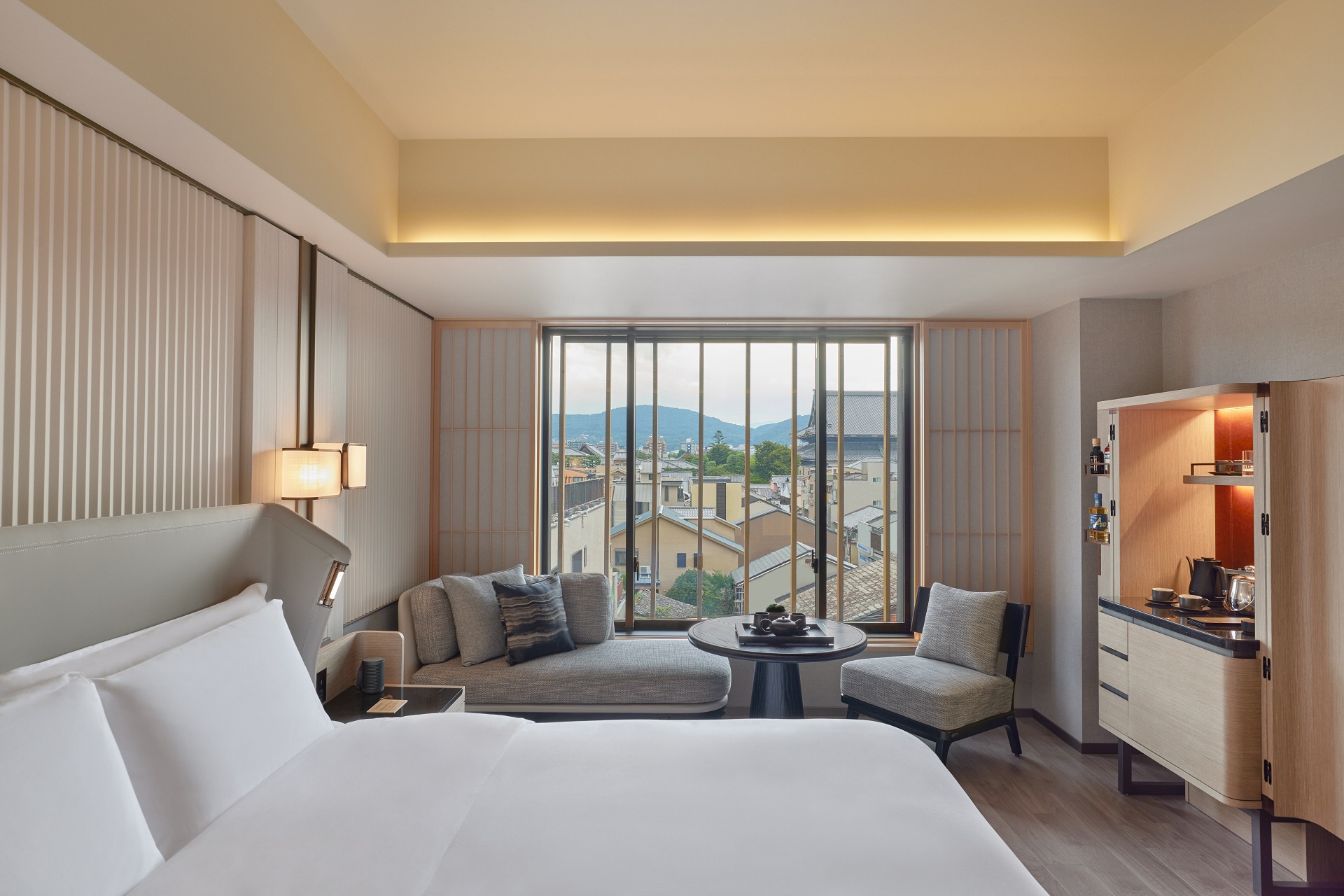 Modern hotel room with twin beds, seating area, and view to a small garden.