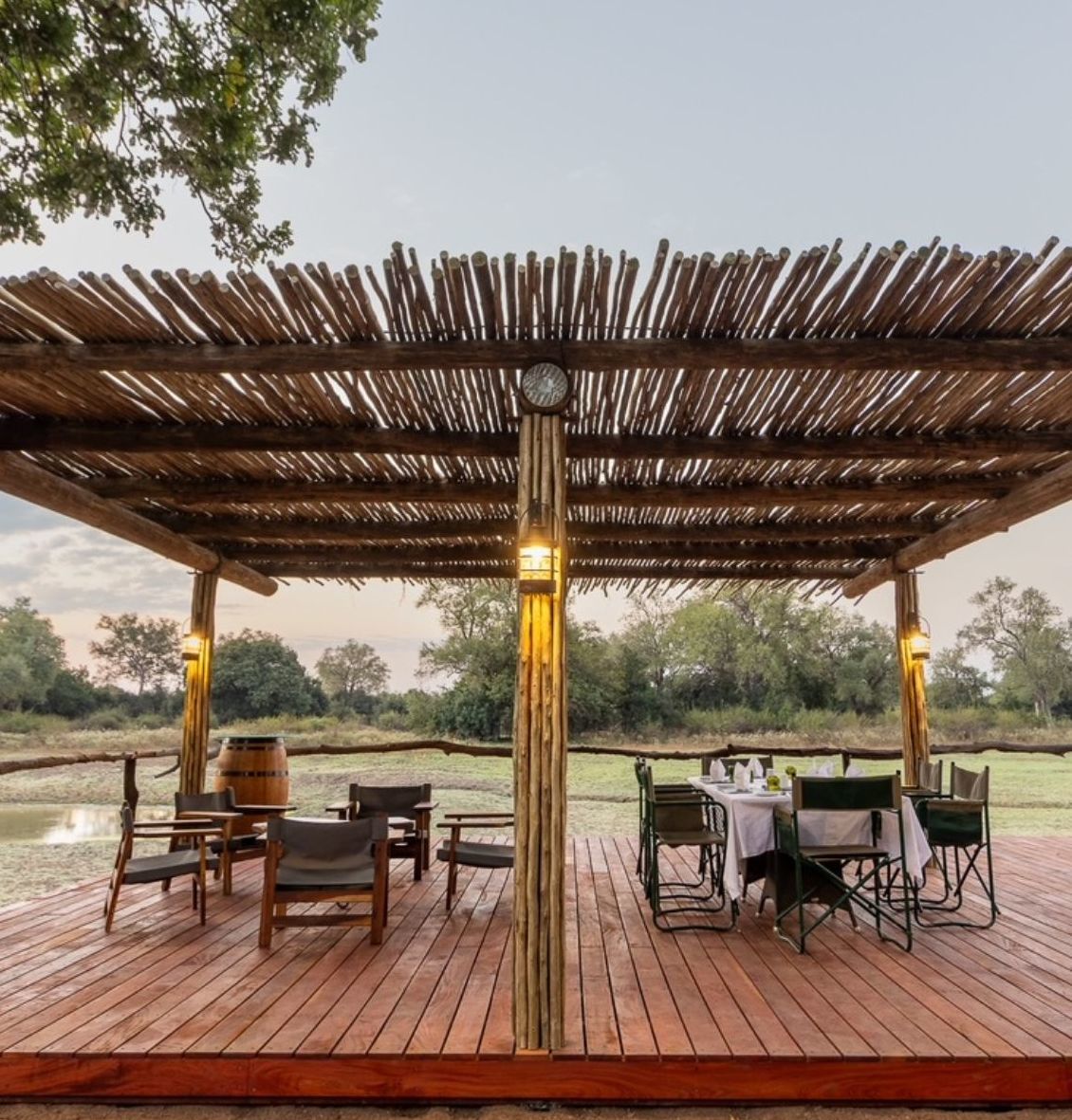 Outdoor dining area with wooden canopy overlooking a serene landscape.