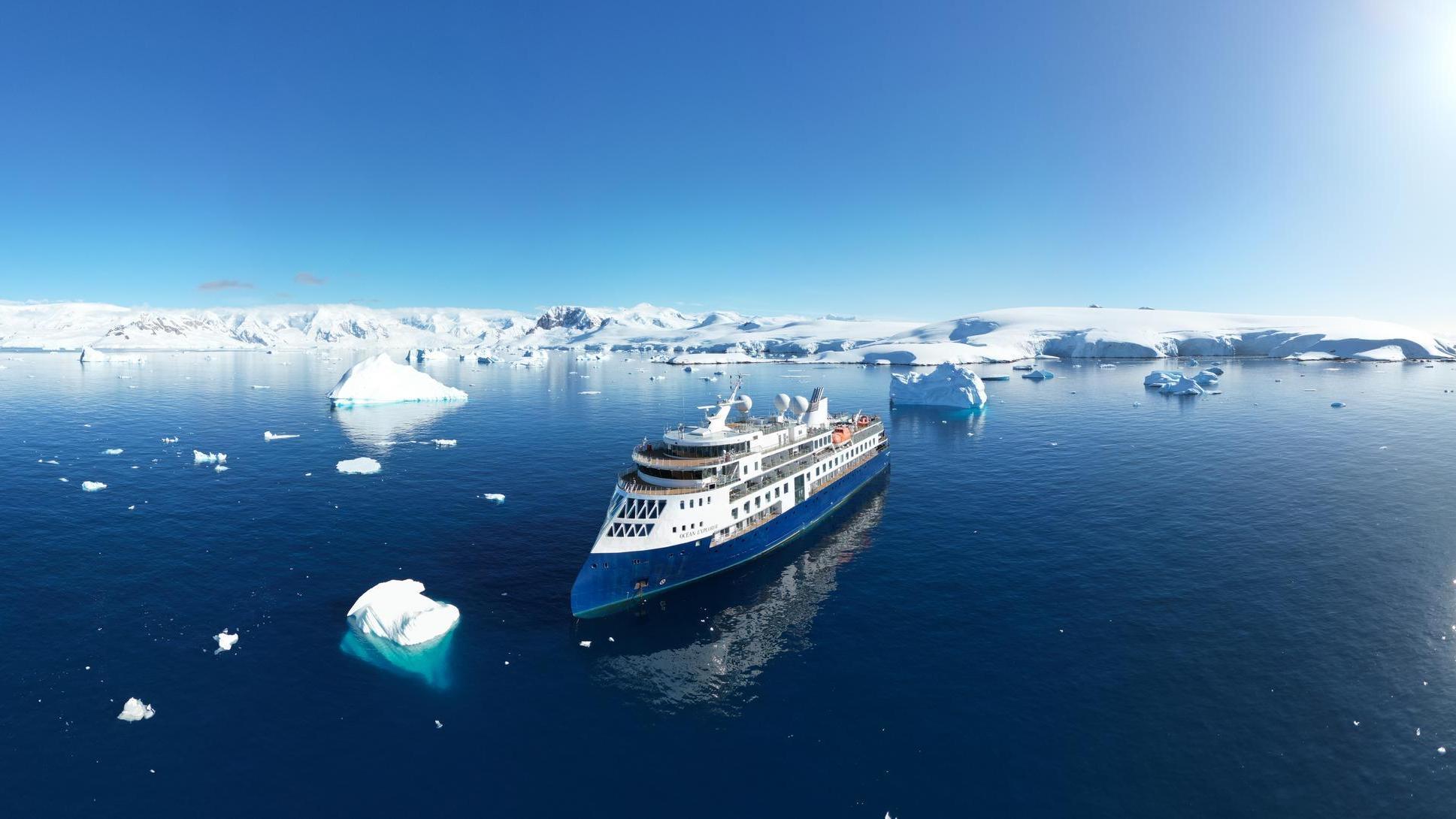 An aerial view of Ocean Explorer cruising between icebergs.