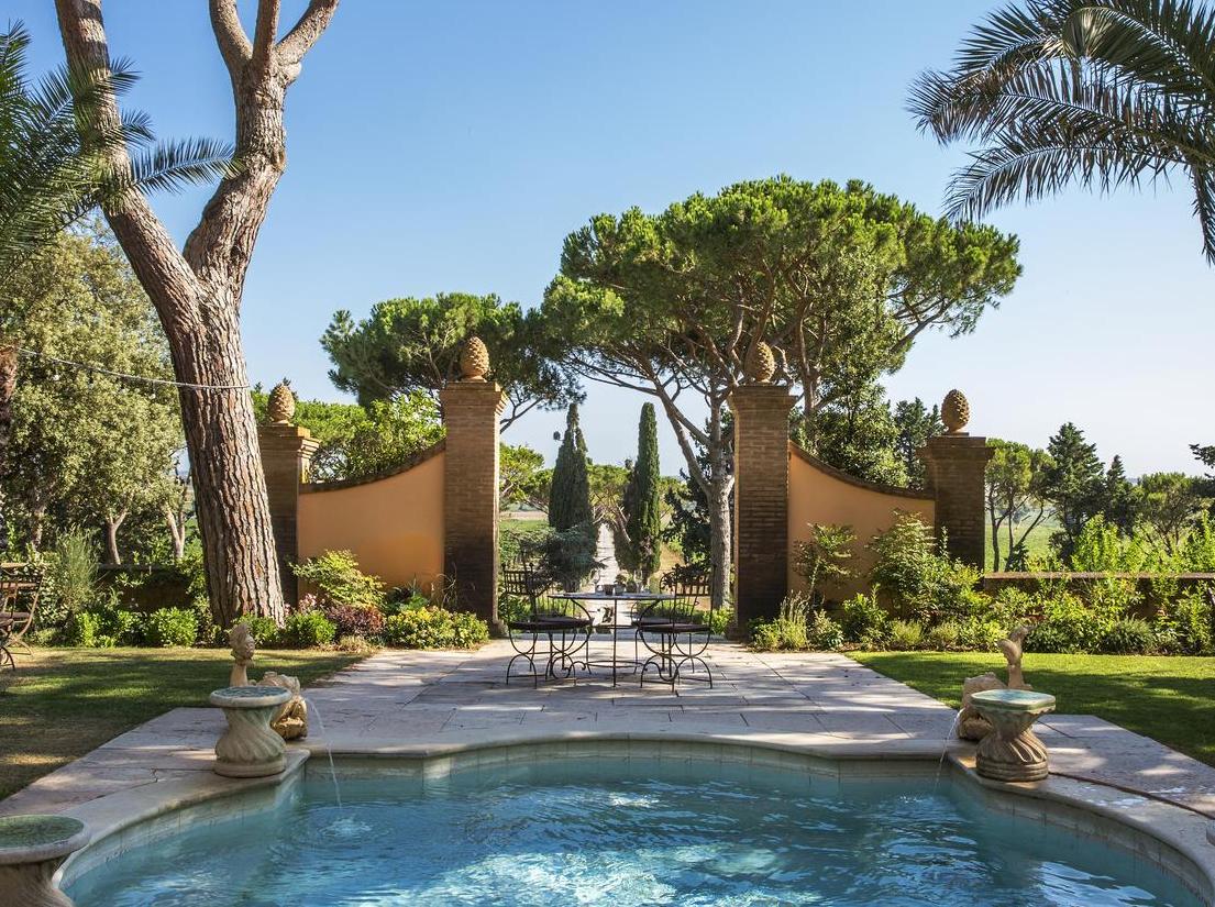 The beautifully manicured grounds at L’Andana Tenuta La Badiola, featuring a fountain and outdoor seating area.