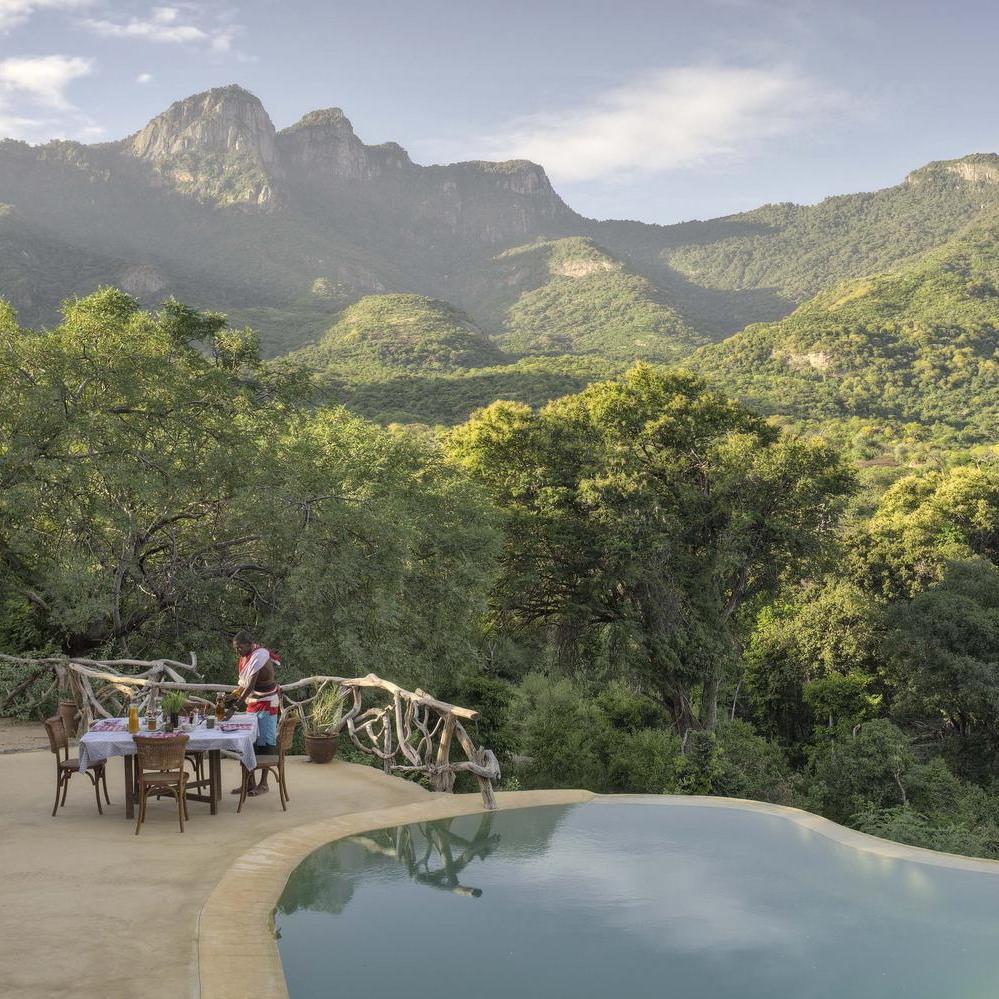 The pool at Sarara Treehouses with a dining table next to it.