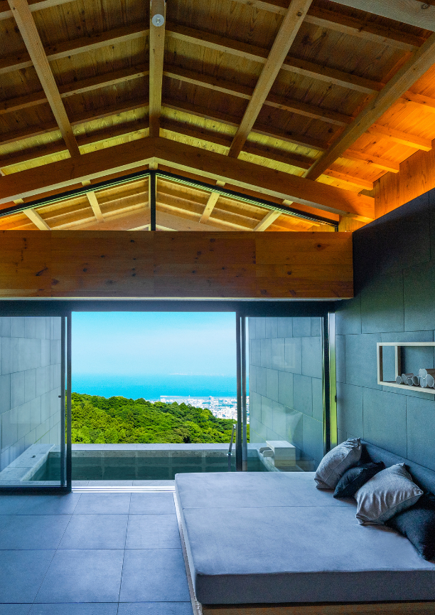 An indoor spa area with a day bed and view of the mountains and sea