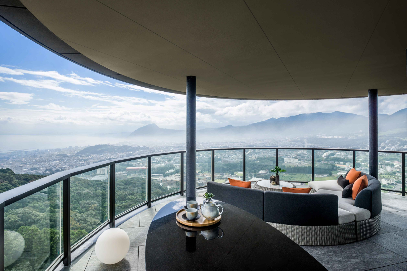 A curving terrace with a round sofa and panoramic views of Beppu, Japan