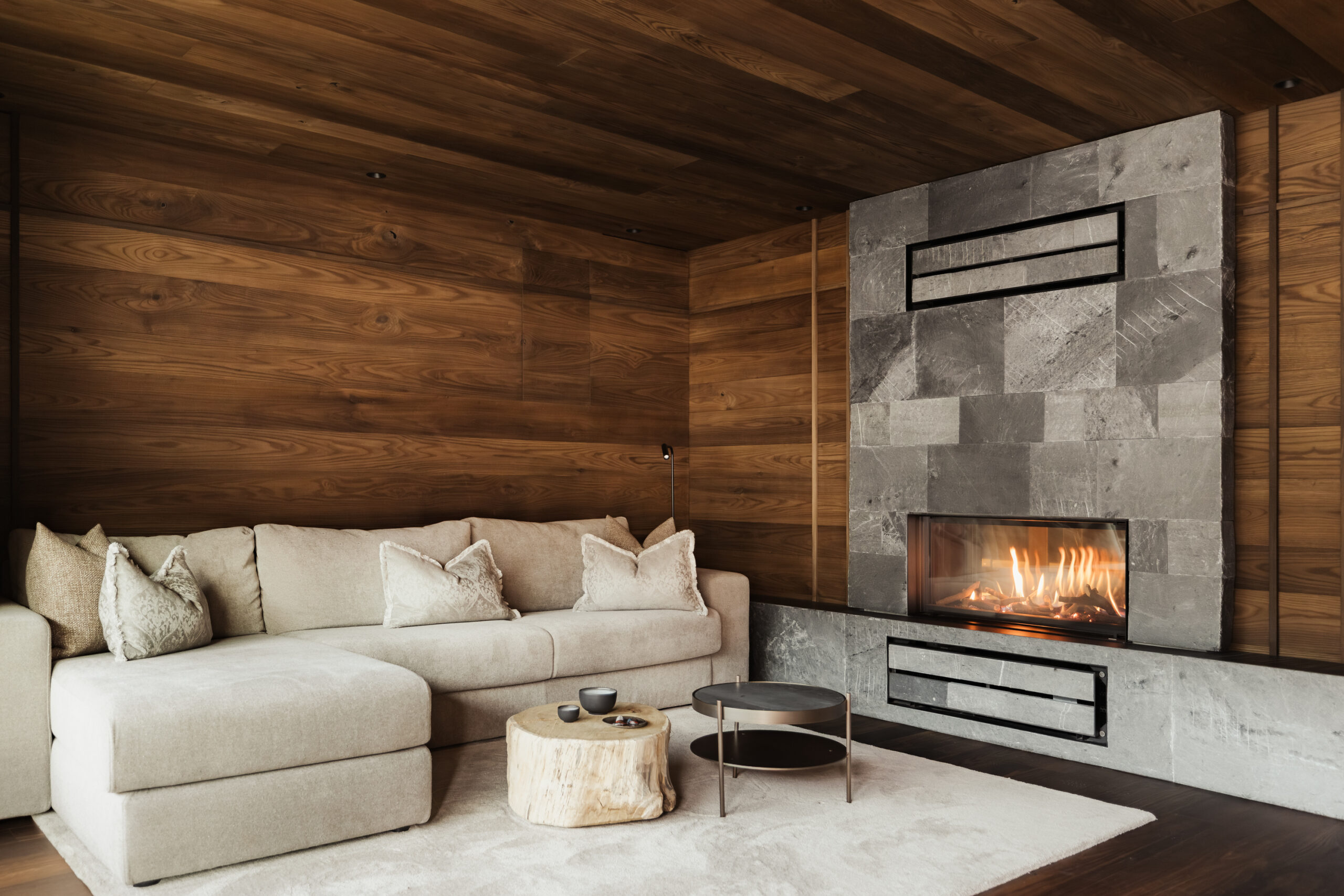 Interior of a suite living area with a beige sofa next to a modern grey stone fireplace.