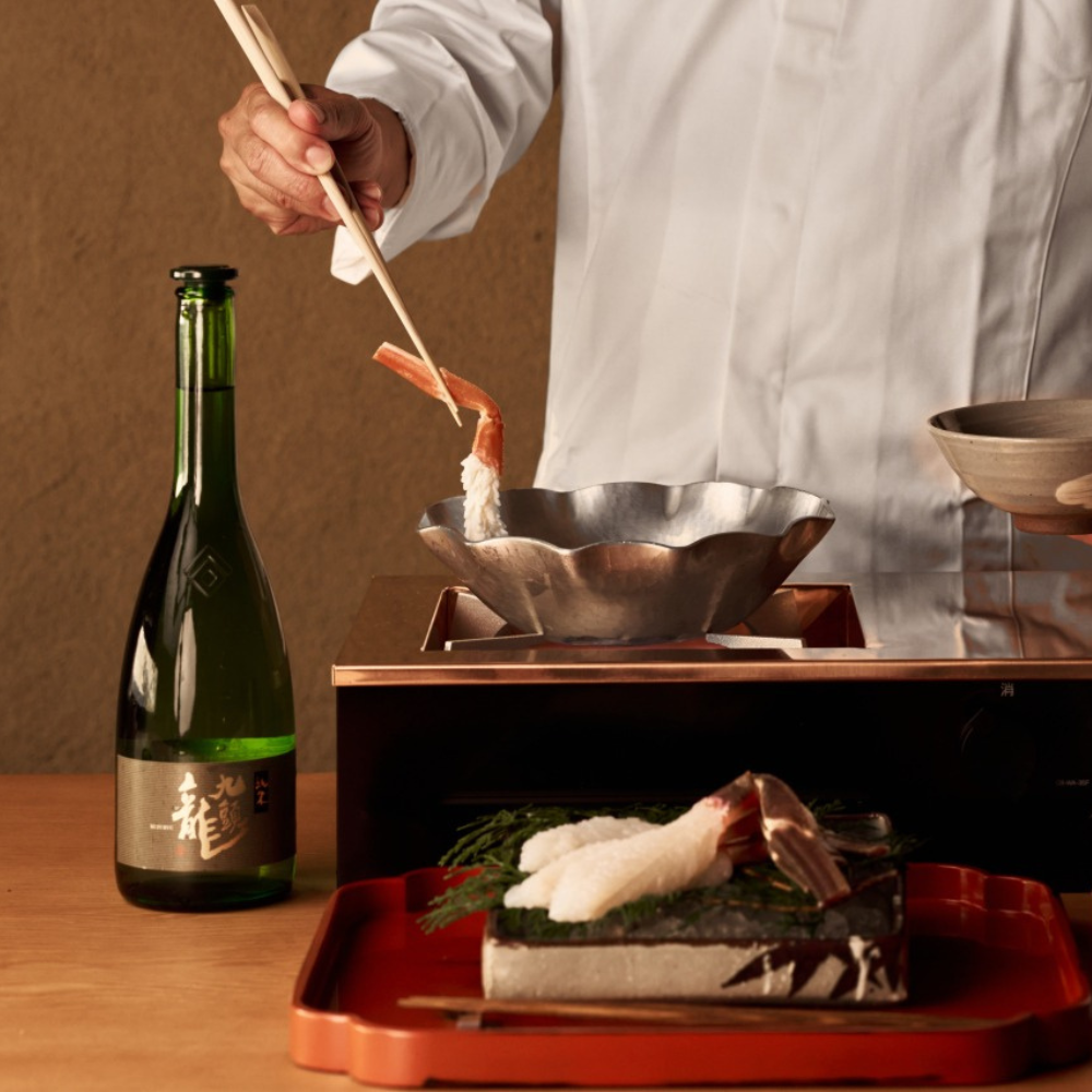 Close-up of a chef placing a crab leg into a metal bowl