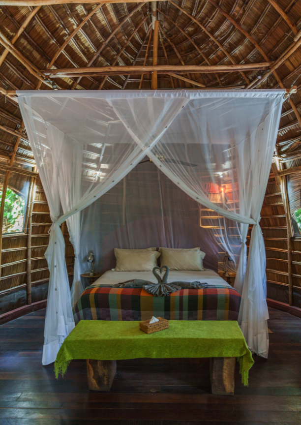 Canopy bed with mosquito net and two towels folded to look like swans