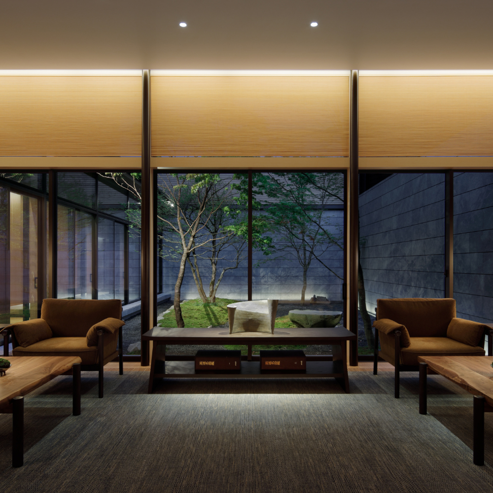 Modern hotel lobby at night with large windows with view of small courtyard