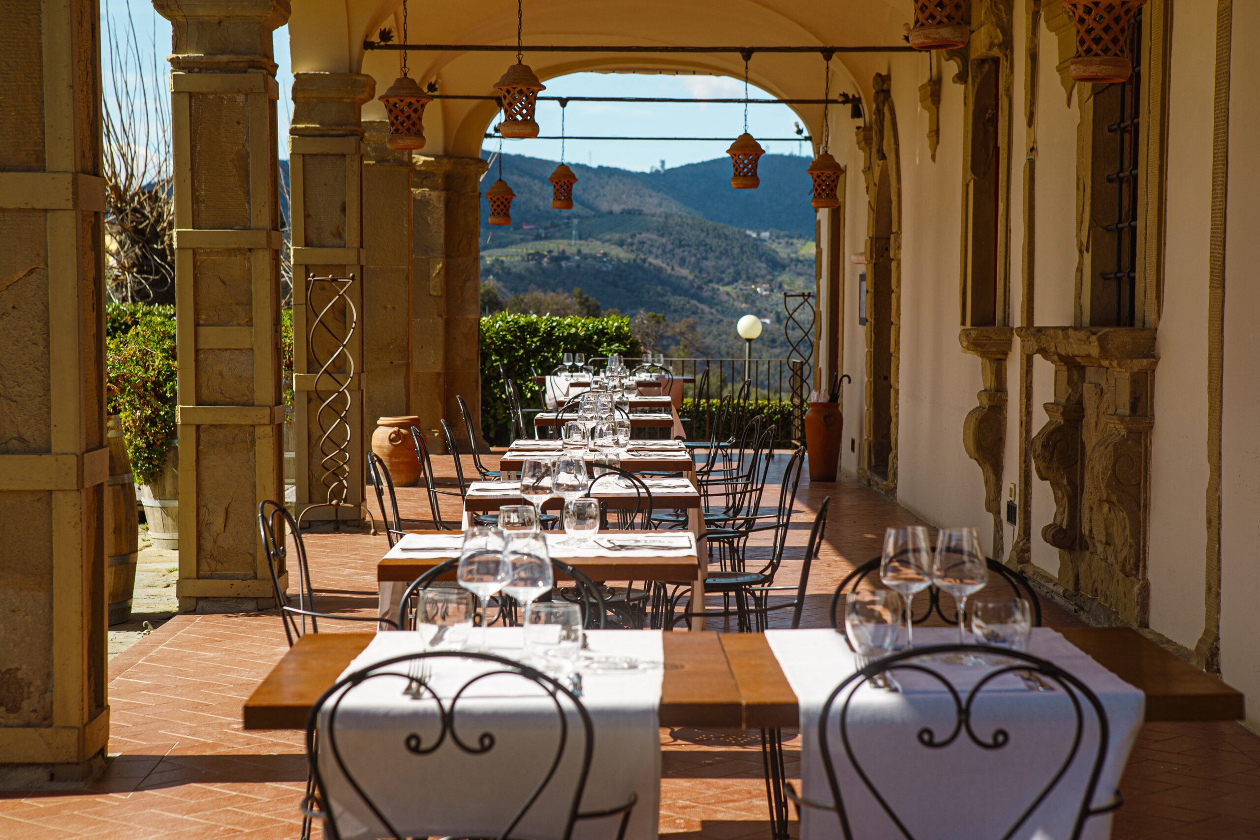 A long terrace with dining tables set up along the columns and views to the countryside.