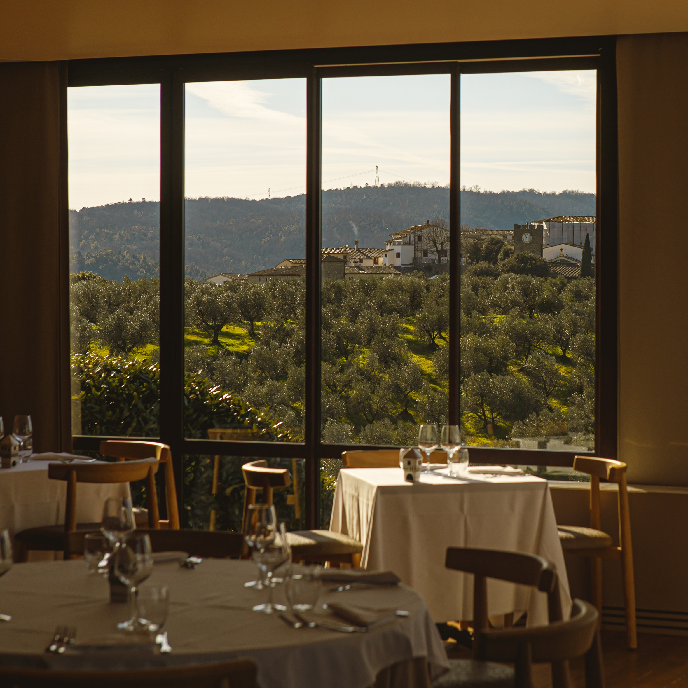 Interior view of a dining space with tables overlooking a window out onto the hills.