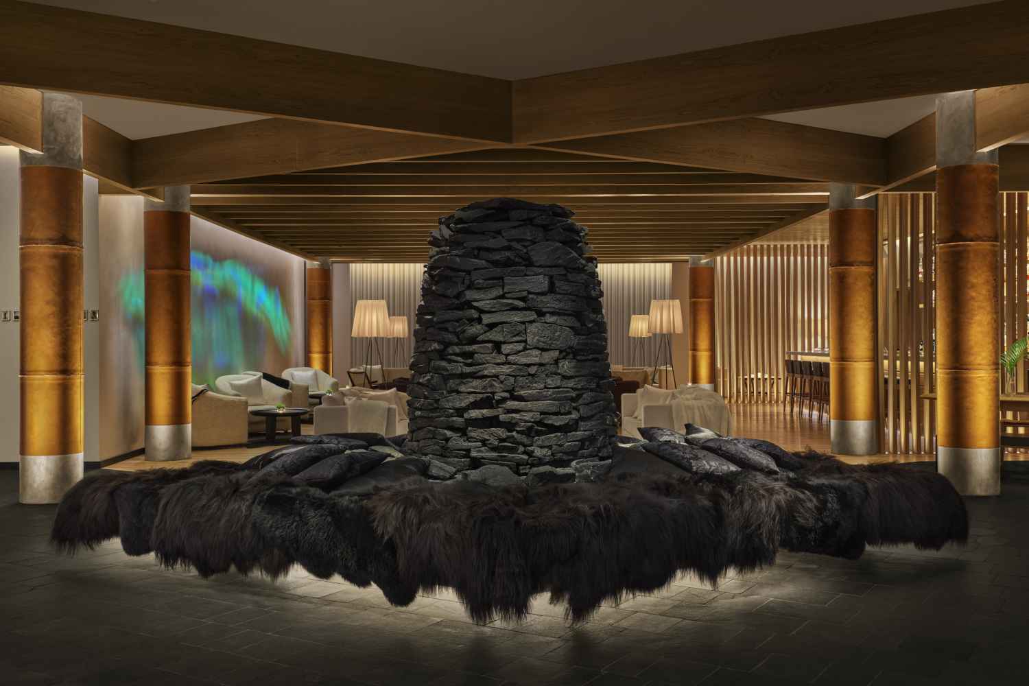 Hotel lobby with dim, warm lighting and a huge black volcanic stone sculpture in the centre of the room.