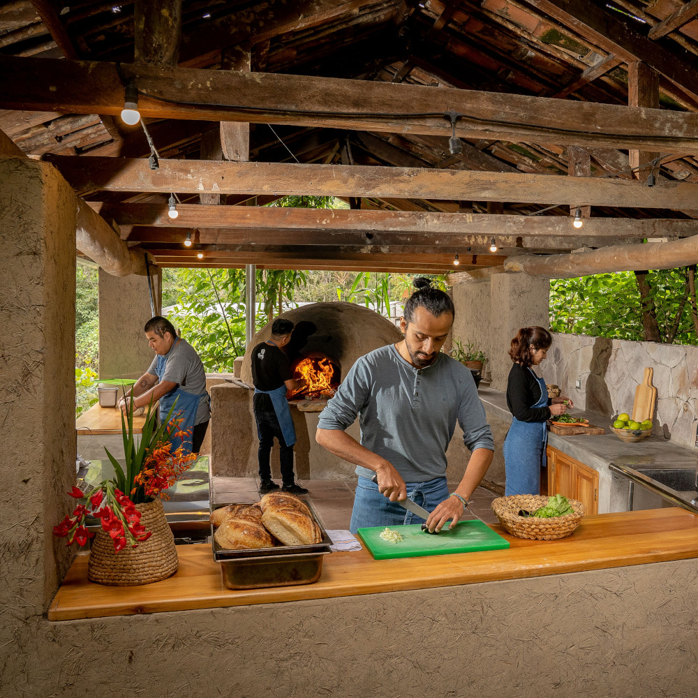 Four people cooking in an open-air covered kitchen.