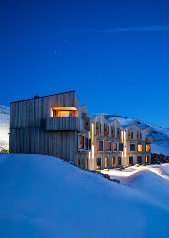 Highland Bases lodge lit up at night time with gently glowing lights reflecting on the snow