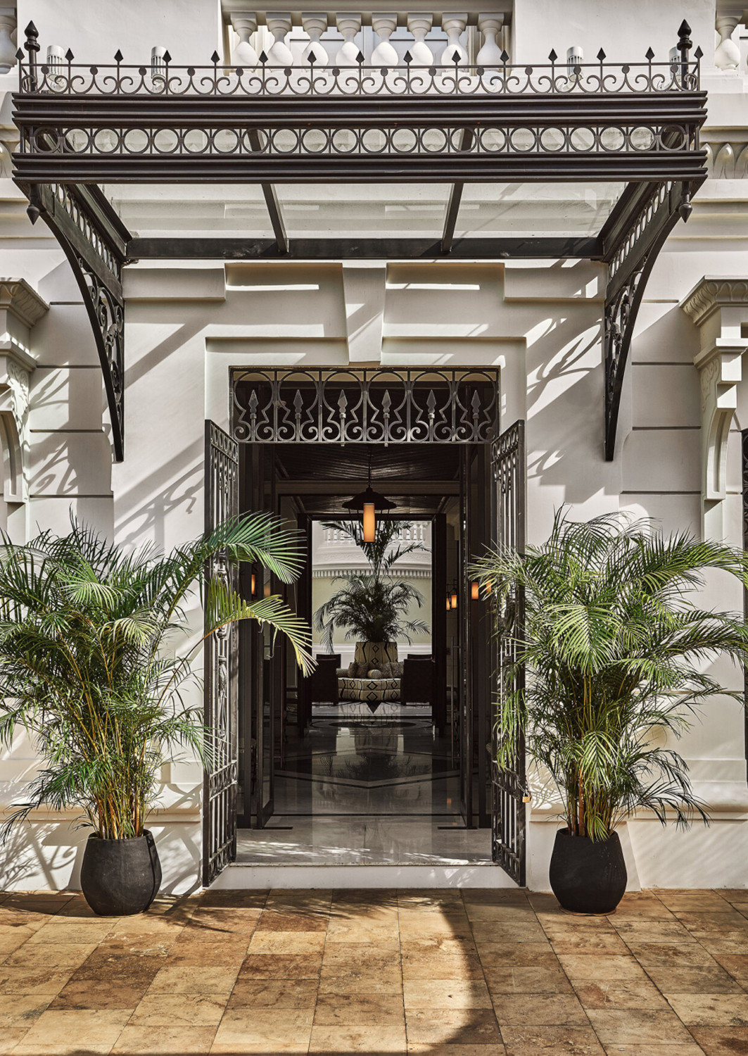 Entranceway with a Beaux Arts doorway and two small palm trees on either side.