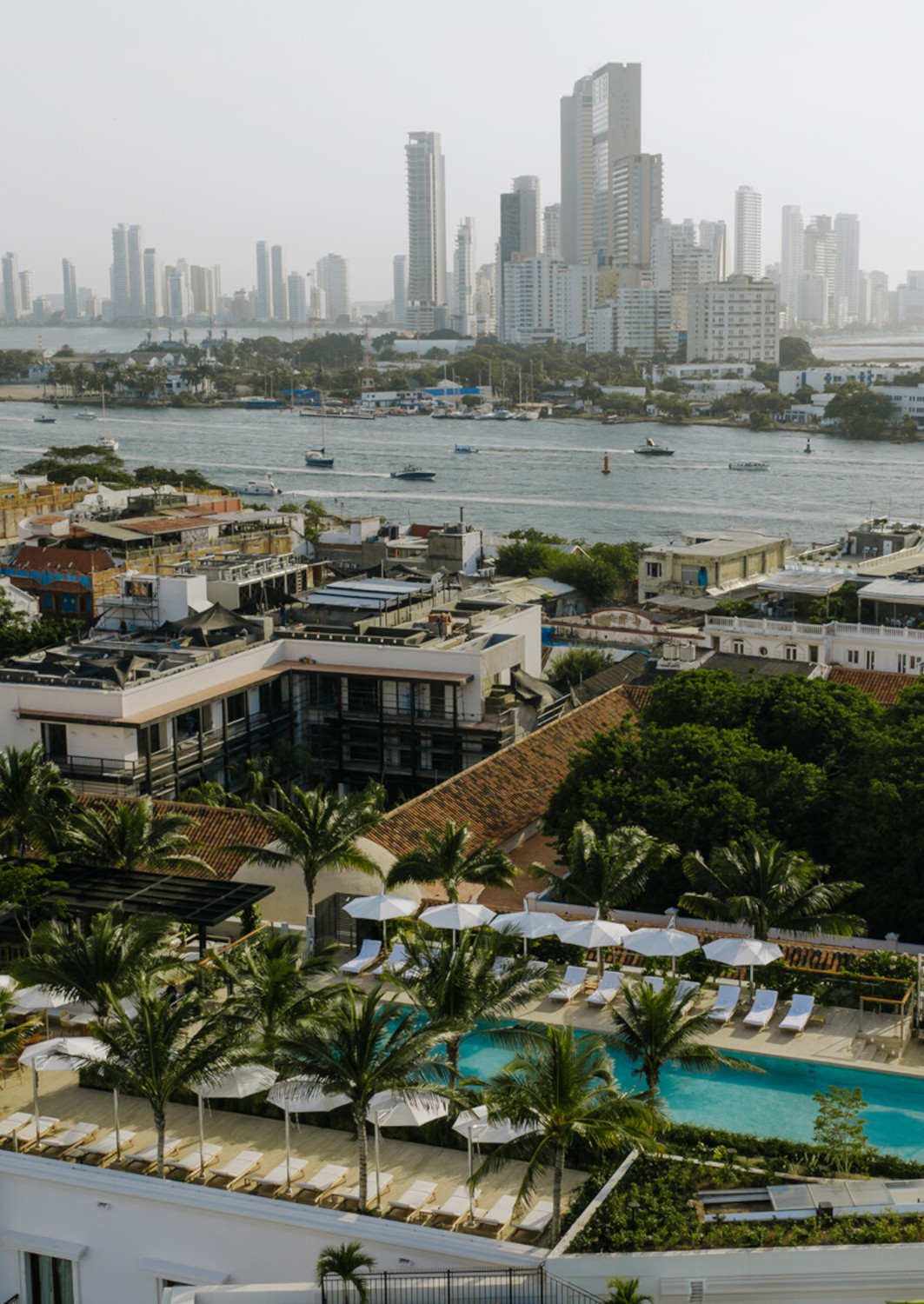 Aerial view over the hotel showing its rooftop pool and views across the water to the skyscrapers of downtown Cartagena