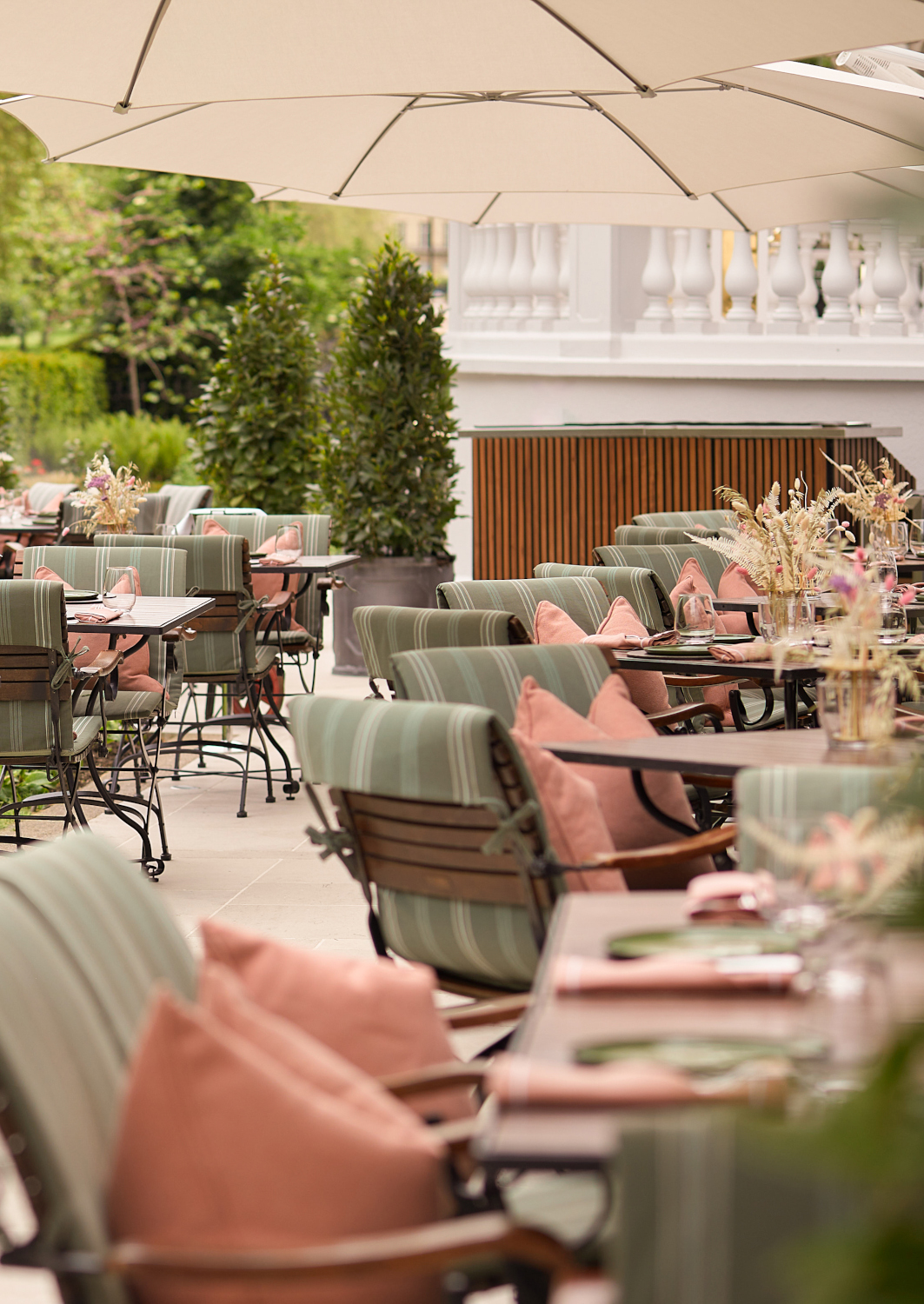 An outdoor patio seating area with tables and chairs with green and pink cushions.
