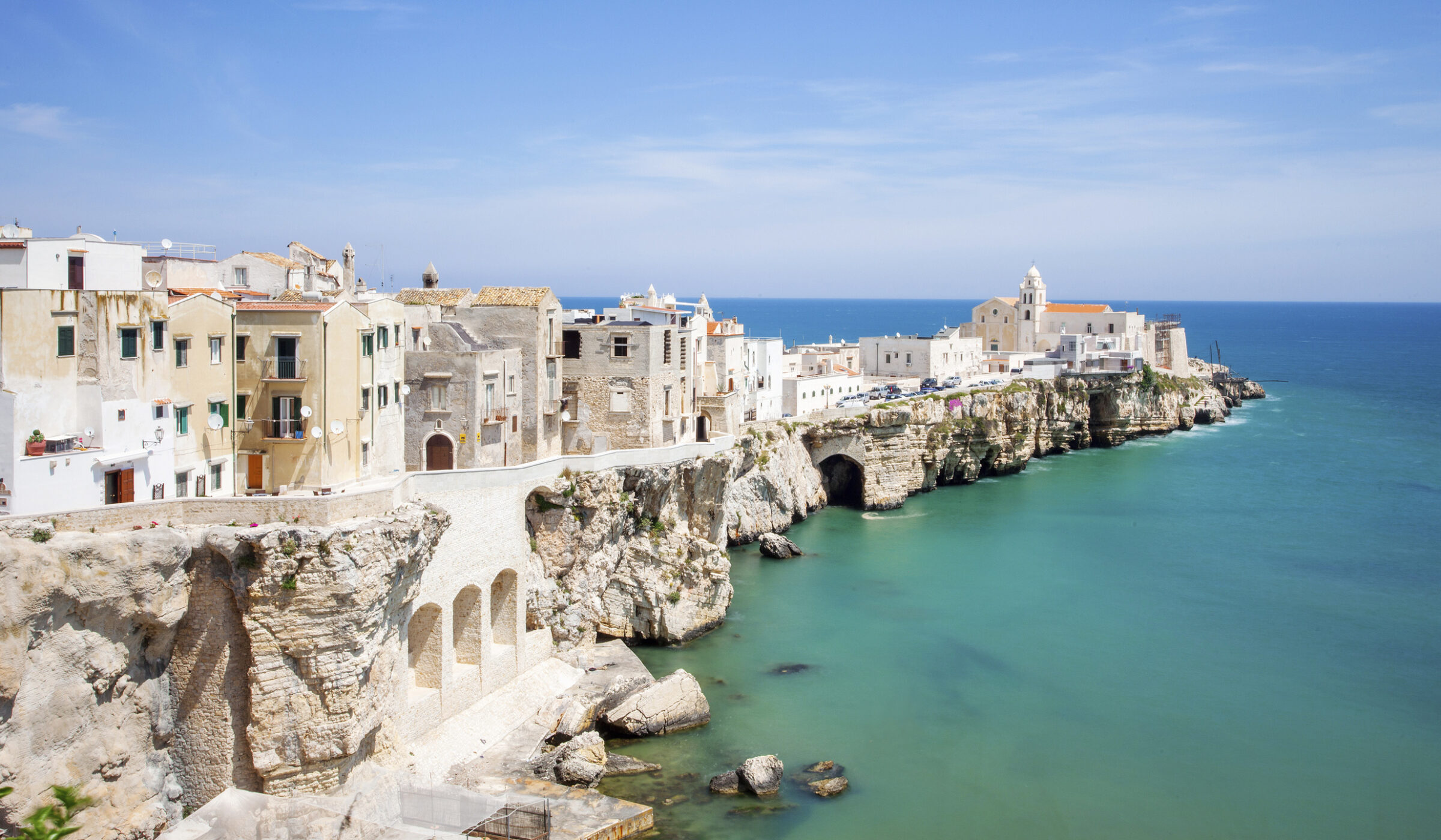 White buildings of a coastal town stretching out over a rocky peninsula during luxury Puglia trips.