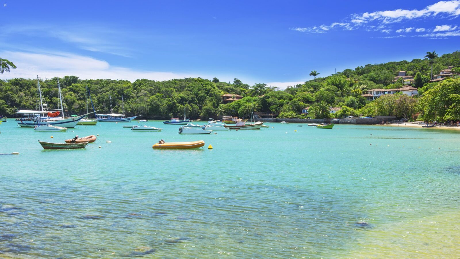 Boats anchored in a tropical bay with green hills for luxury Latin America honeymoon tours.