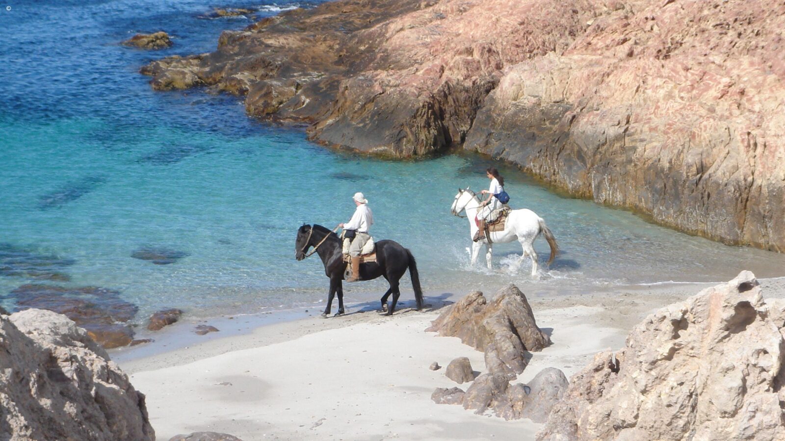 Horseback riding on a white sand beach during luxury Latin America honeymoon vacations.
