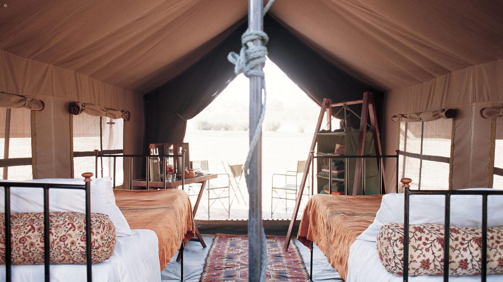 Interior view of safari tent accommodation with two single beds, clothes storage and small table