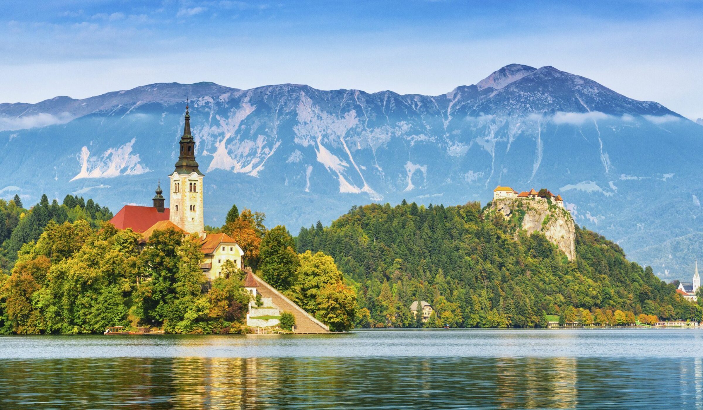 View of church on a small island in the middle of Lake Bled, an alpine lake in Slovenia with snow-capped mountains around it