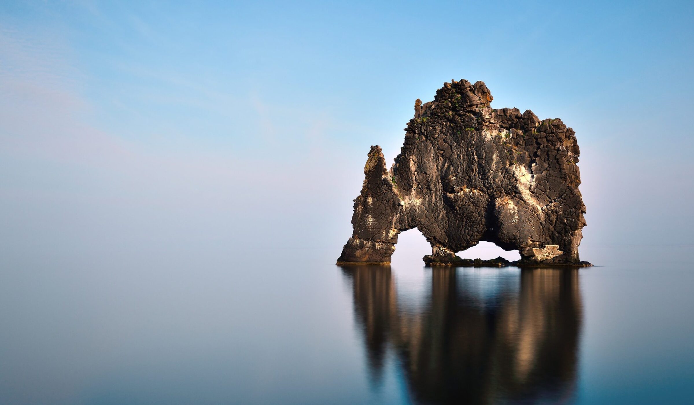 Hvítserkur rock formation rising from the glassy water in northern Iceland