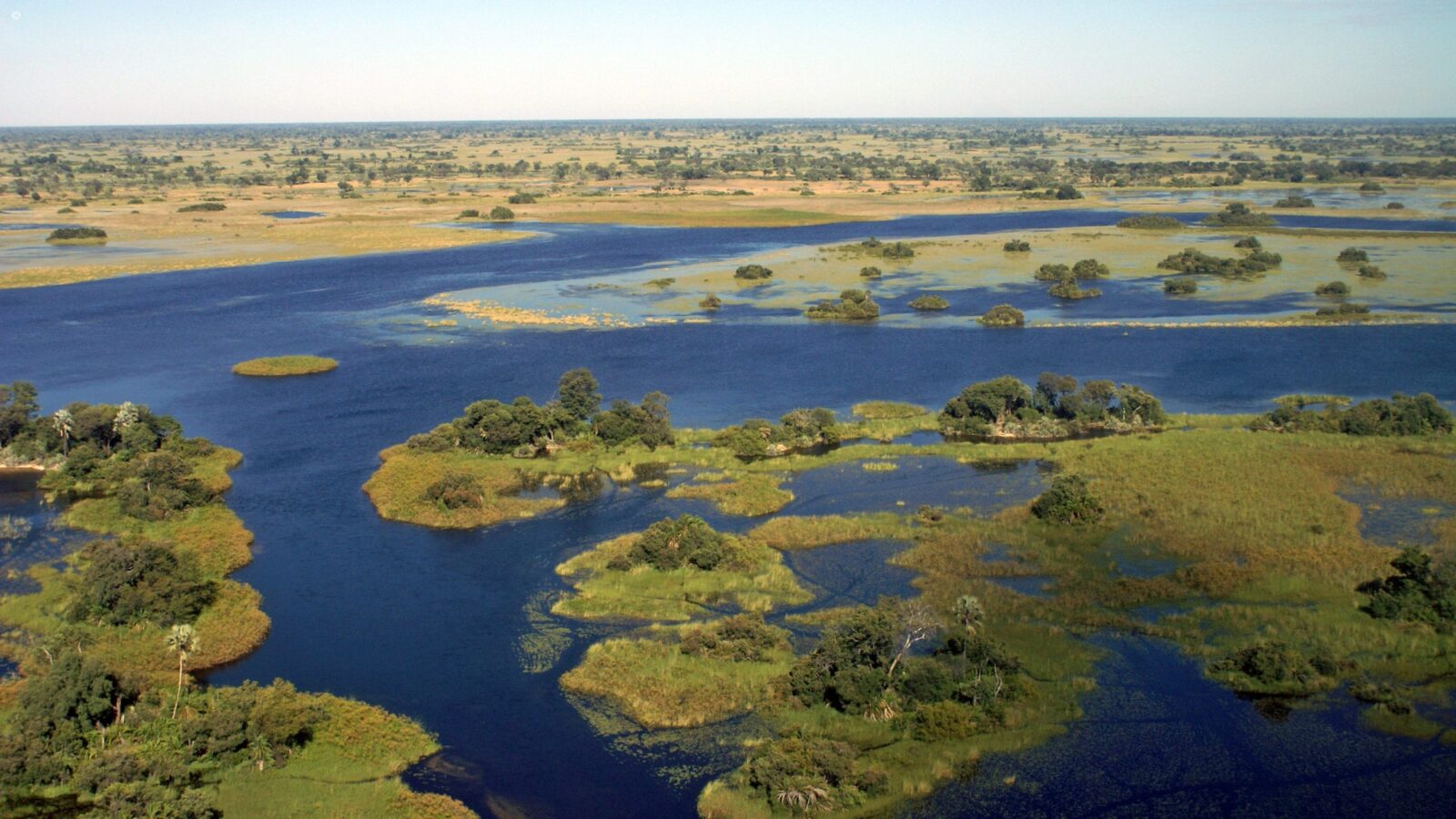 Aerial view of blue waterways and green islands on luxury Okavango Delta safaris.