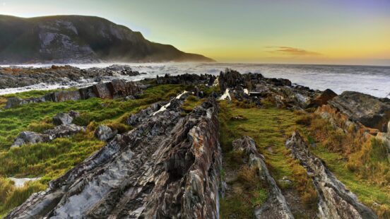 Rugged rocky coastline and crashing waves at sunset viewed on luxury Eastern Cape tours.