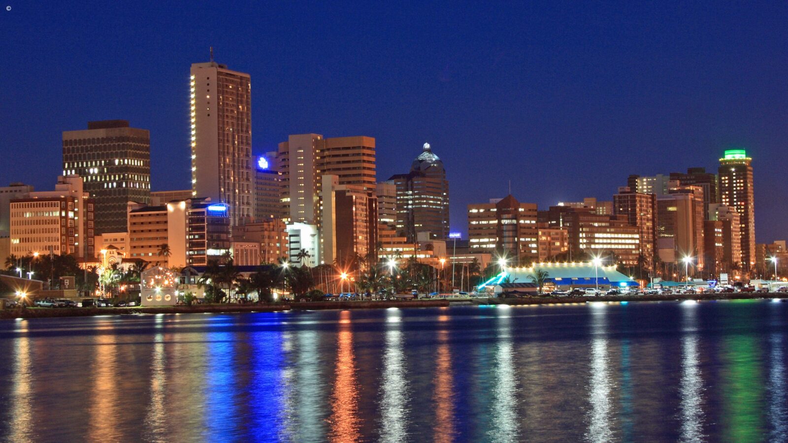 Night skyline with lit buildings reflecting in the water during luxury Durban tours.