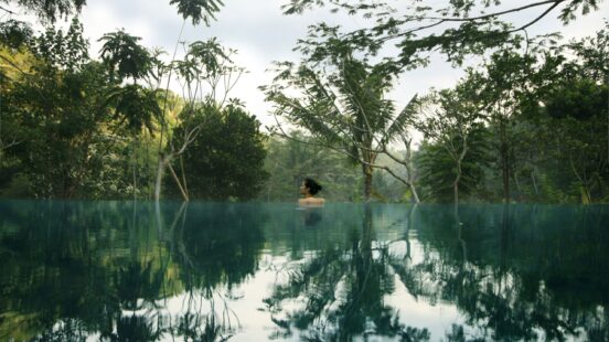A lady in the mystical infinity pool overlooking the treetops