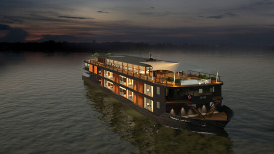A large, modern luxury cruise boat illuminated at night while sailing on a calm river under a dark sky.