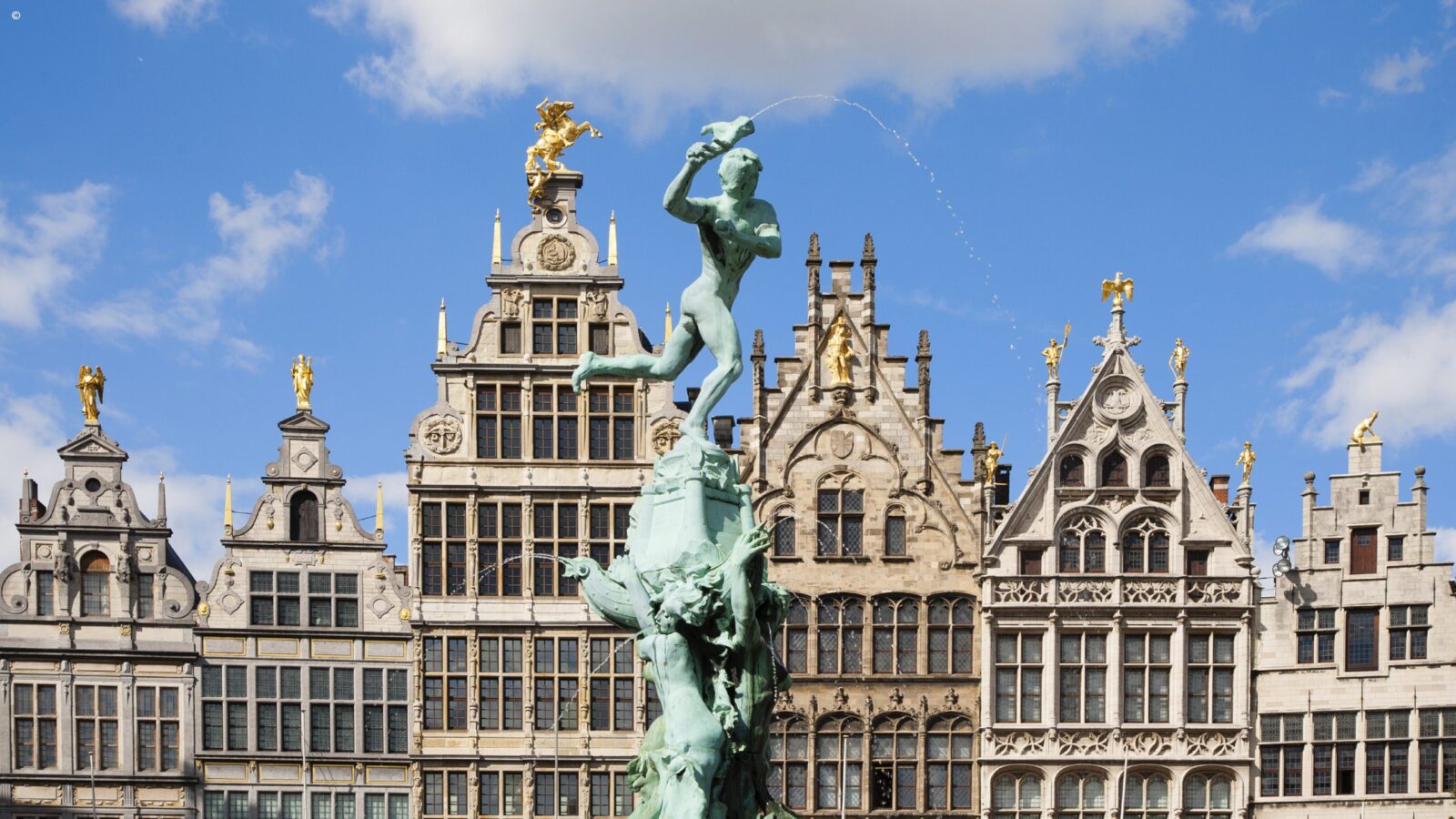 Statue of a man running a top a fountain in a central square surrounded by opulent gabled buildings in Belgium