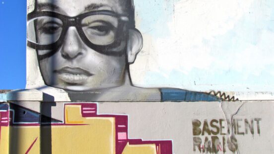 A wall mural of a person with large glasses next to the words Basement Radio.