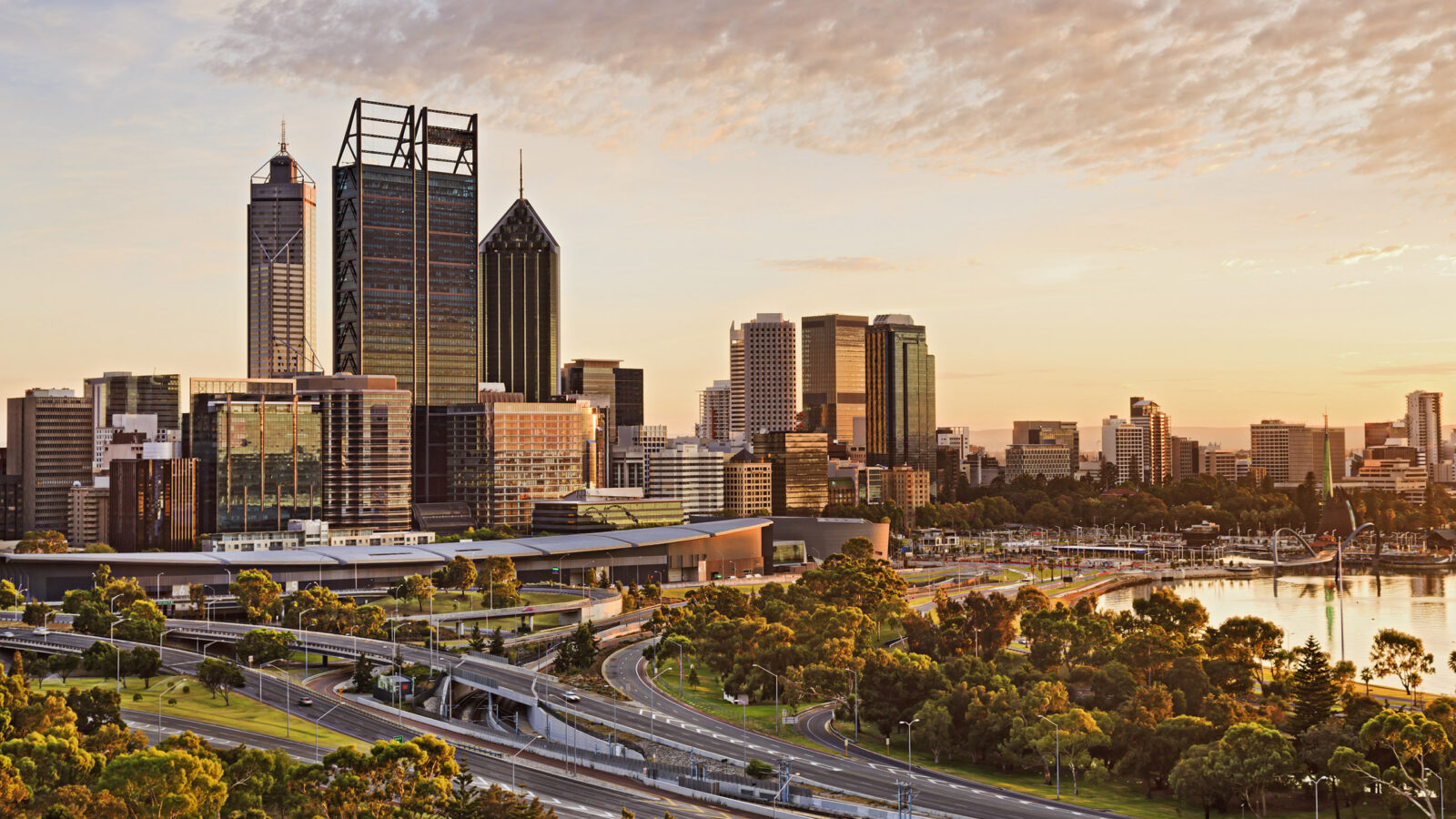 Western Australia capital city Perth at sunrise during golden hour. Bright warm sun light sheds on skyscrapers and city-line.