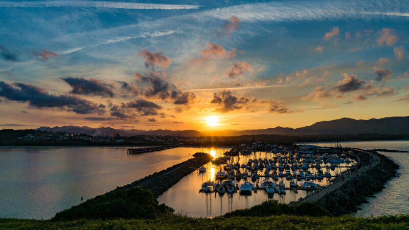 Sunset landscape of coastal city with dramatic clouds and plane trails on the background. Muttonbird Island Nature Reserve, Coffs Harbour, Australia